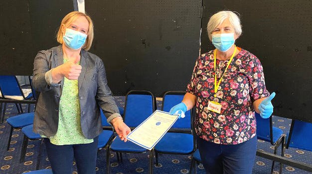 A volunteer at a COVID-19 vaccination centre is handed a certificate by a team leader to say thank you for volunteering